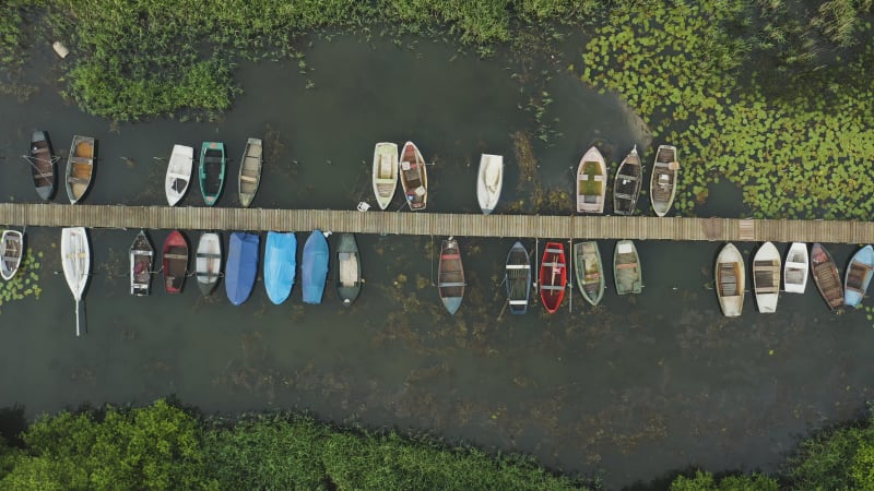 Top down view of small boats by the wooden dock on the lake