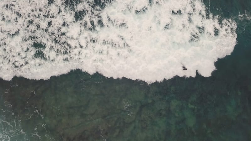 Aerial view of a man surfing at an agitated sea near Lošinj coastline.