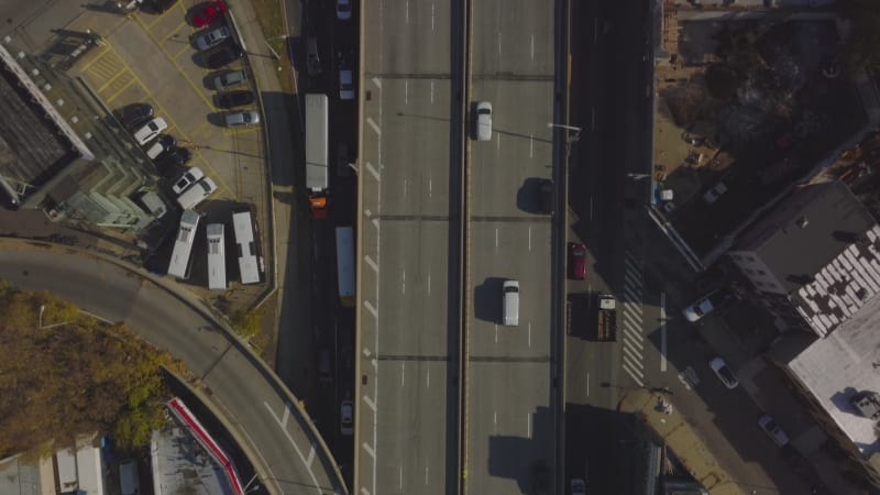 Aerial birds eye overhead top down panning view of traffic on multilane highway leading trough town borough. Cars driving on elevated road. Queens, New York City, USA