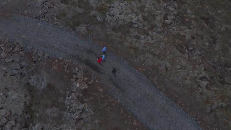 Overhead view four people walking pathway in rocky desolated highlands in Iceland. Top down view of group tourist mountaineering strolling trail trekking outdoors