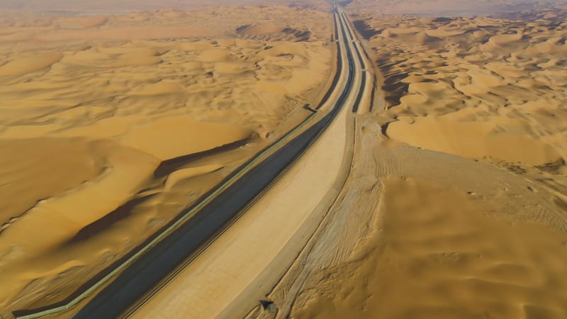 Aerial view above of train rail crossing vast desert.