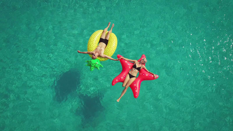 Aerial view of man and woman floating on inflatable.