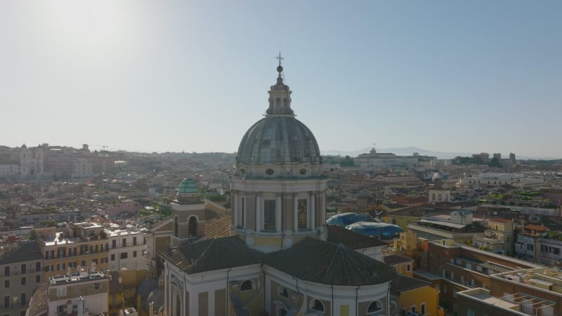 Orbit shot around church tower with large dome. San Carlo al Corso and buildings in city in background. Rome, Italy