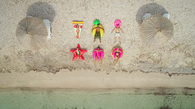 Aerial view of people lying on big inflatable mattresses on beach.