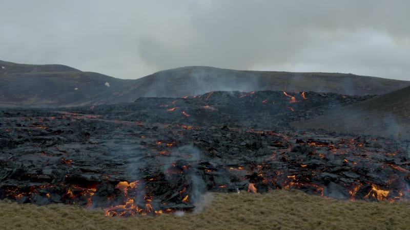 Smoking lava flow on dark volcanic landscape