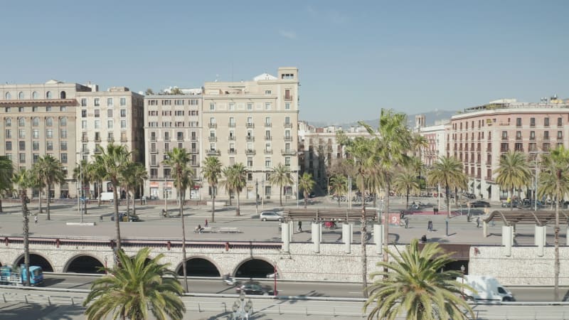 Barcelona Residential Apartment Buildings with Palm Trees and wind blowing on beautiful Sunny Day, Car traffic passing by and pedestrians walking