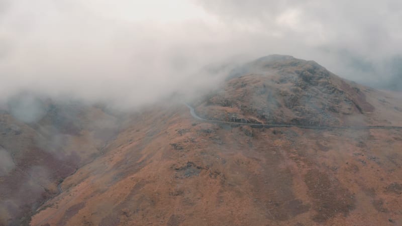 Car driving along a mountain top shrouded in fog