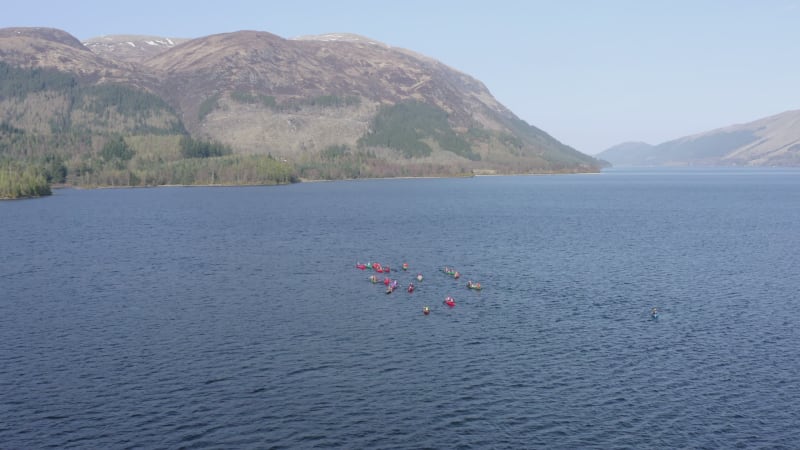 Aerial View of Canoeists in a Lake Surrounded by Mountains and Nature