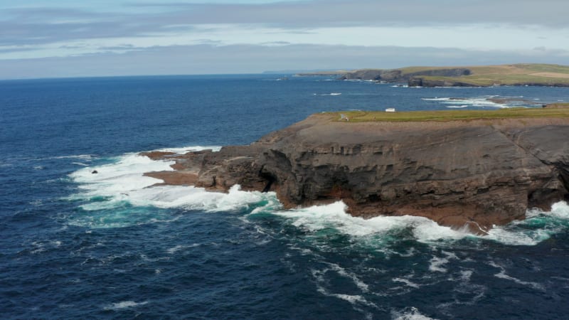 Amazing coastal scenery. Blue ocean water crashing on rock cliffs on sea coast. Kilkee Cliff Walk, Ireland