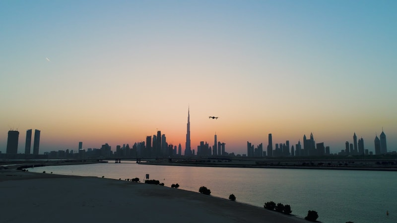 Aerial view of drone filming Dubai cityscape during scenic sunset.