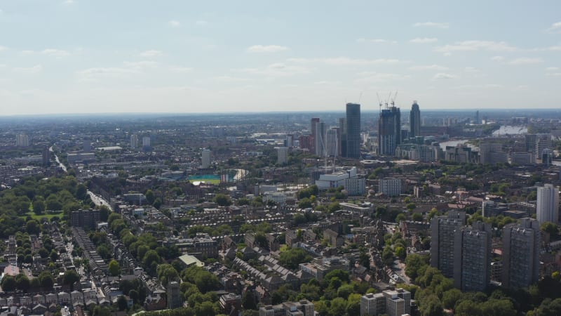 Ascending panoramic footage of large city. Housing district and tall office buildings in distance. London, UK