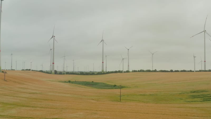 Wind Turbine farm on rich yellow agriculture field rotating by the force of the wind and generating renewable energy in a green ecologic way for the planet in Germany