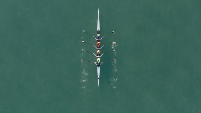 Sport Canoe with a team of four people rowing on tranquil water, Aerial view.