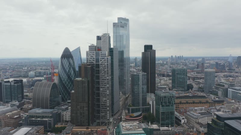 Backwards reveal of buildings around financial and economic hub in City district. Group of modern skyscrapers. London, UK