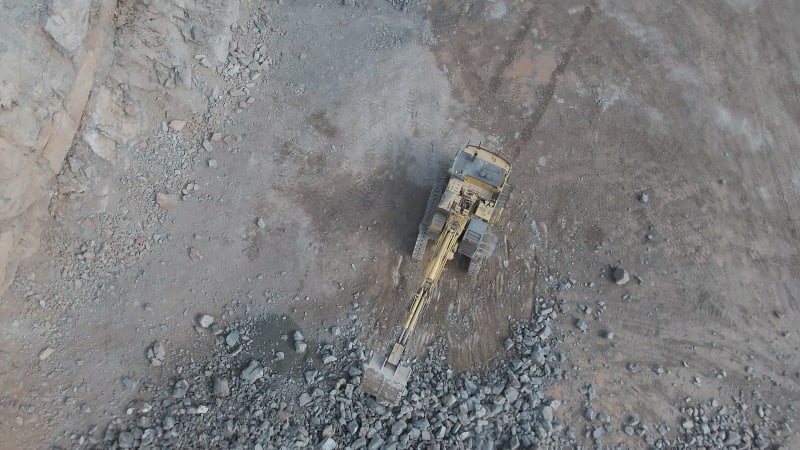 Digger Working on Blasted Rocks in a Quarry