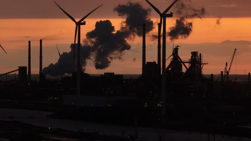 Aerial shot of windturbines at sunset in front of IJmuiden industrial site