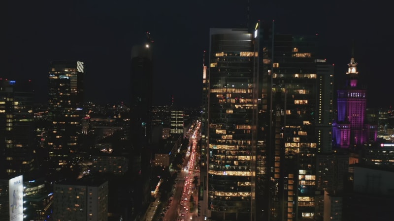 Forwards fly around downtown skyscrapers at night. Traffic jam in street bellow. Endless stream of car lights. Warsaw, Poland