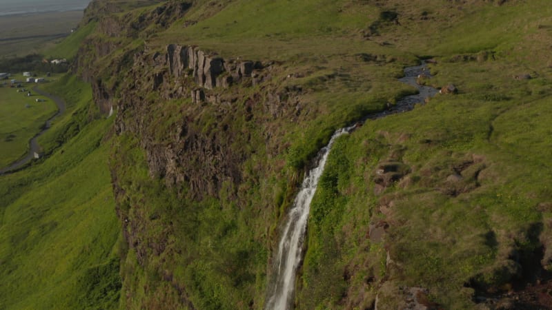 Orbit overhead drone view of majestic Seljalandsfoss waterfall in Iceland, most famous travel destination. Top down view of water flowing over green mossy cliffs. Beauty on earth