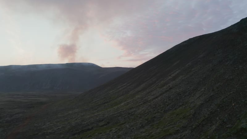 Birds eye drone lifting off revealing incredible Iceland highlands panorama at sunset. Aerial view of icelandic hills with smoking steaming from hot craters fumaroles