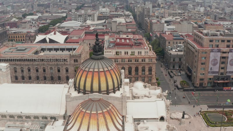 Drone camera flying around colorful dome with bird sculpture of Palace of fine arts (Palacio de Bellas Artes) in historic city center. Mexico city, Mexico.