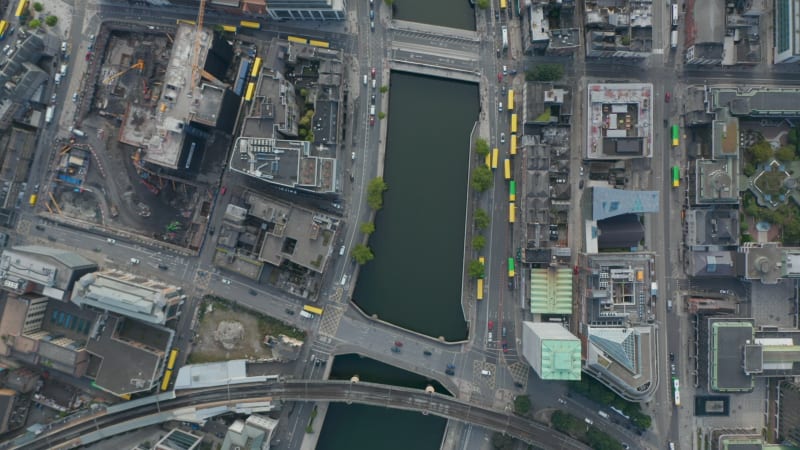 Aerial birds eye overhead top down panning view of traffic in town streets. Public transport buses with yellow roof. Dublin, Ireland