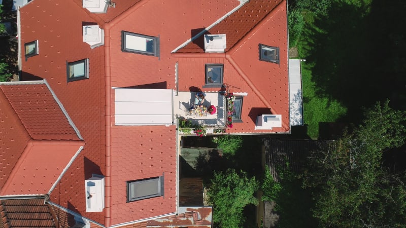 Aerial view of family having breakfast on rooftop balcony.