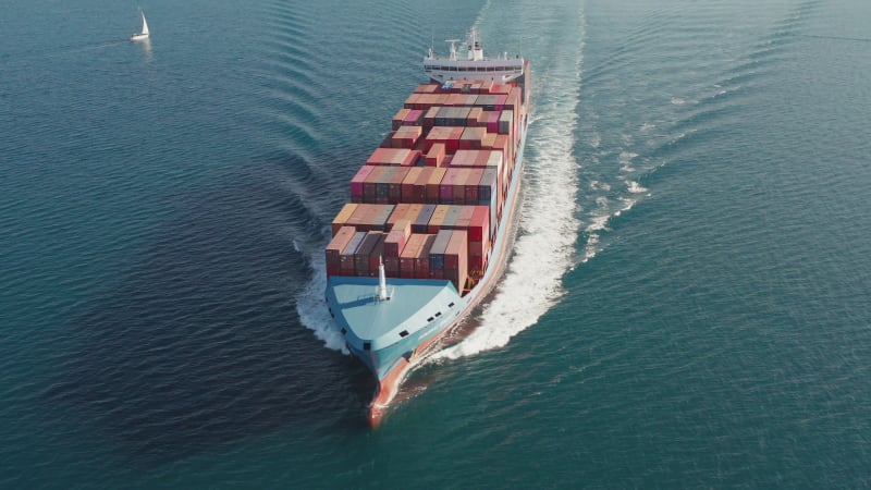 Large loaded Container Ship roaring across the open sea, Aerial view.