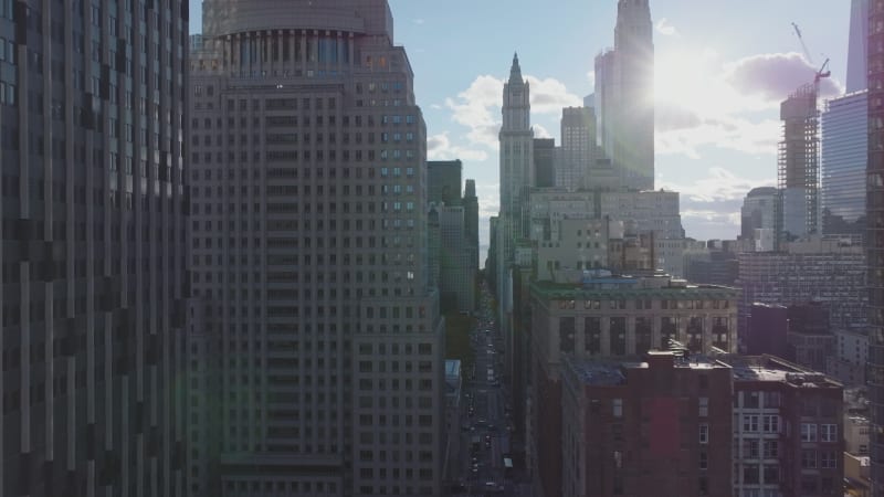 Fly between high rise buildings against sunshine. Revealing view of City hall and surrounding park. Manhattan, New York City, USA