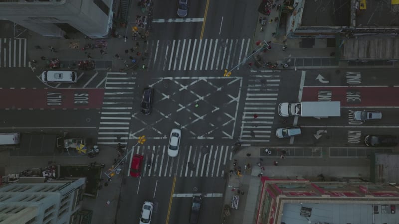 Aerial birds eye overhead top down ascending footage of cars driving through crossroads, pedestrians crossing street on  Manhattan, New York City, USA