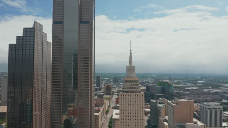 Aerial view of tall building with spike and large clock. Forwards fly to Mercantile National Bank Building. Dallas, Texas, US