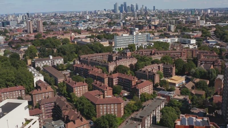 Aerial view of brick apartment houses in Southwark borough. Group of downtown skyscrapers in distance. London, UK