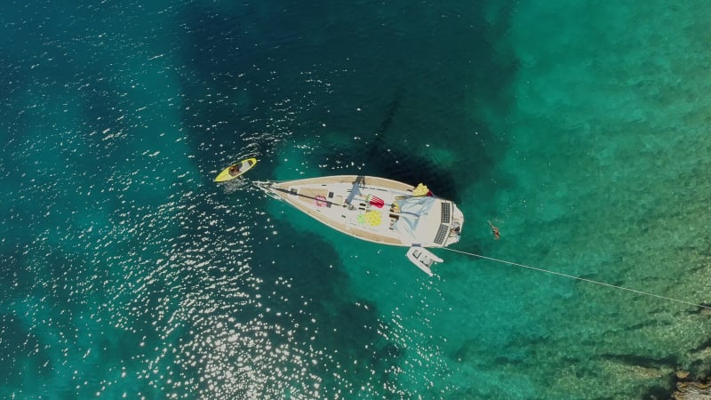 Aerial view of paddle board next to boat anchored on the coast of Varko.