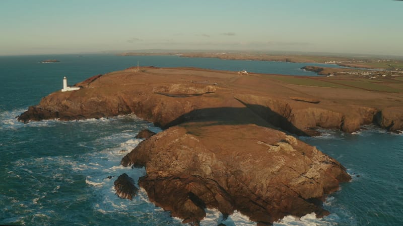 Aerial view of Cornwall coastline with a lighthouse, United Kingdom.