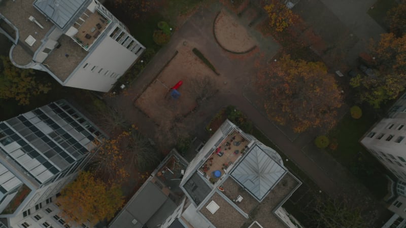 Scenic Top View Shot of a Ghetto Neighbourhood Backyard with Playground slide in between apartment blocks Aerial Birds Eye Overhead Top Down View