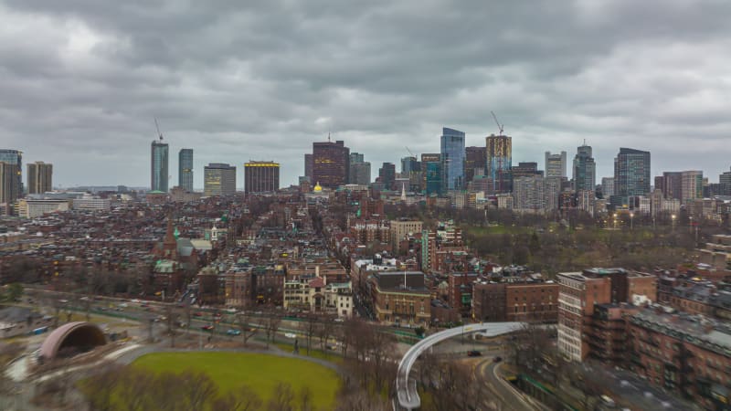 Forwards fly above residential urban borough. Hyper lapse short of dusk in large city. Modern office buildings in background. Boston, USA