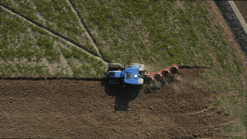 Aerial view of a tractor plowing a field in Lomellina, Po Valley, Italy.