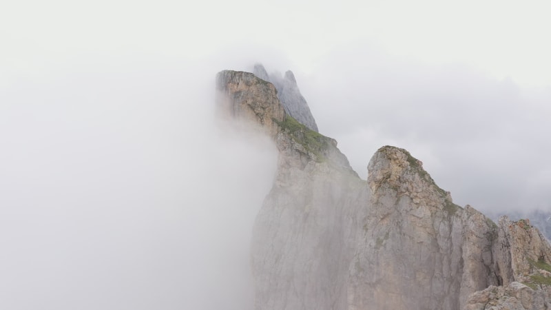 Revealing drone shot flying past majestic mountain ridge towards green Summer meadows of Seceda in Italy