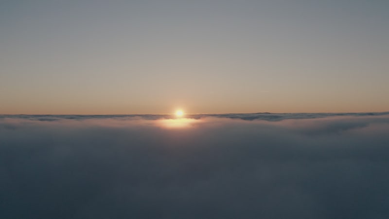 Aerial dolly view of flying above the clouds in warm evening light