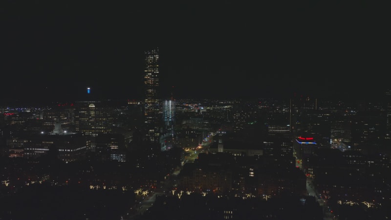 Aerial ascending footage of large city at night. Buildings with lighted windows. High rise office buildings. Boston, USA