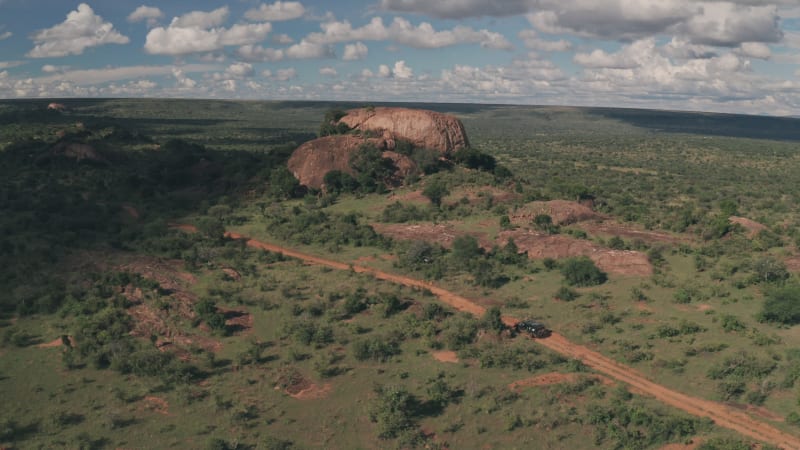 Following off road vehicle driving past rock formations in Kenya