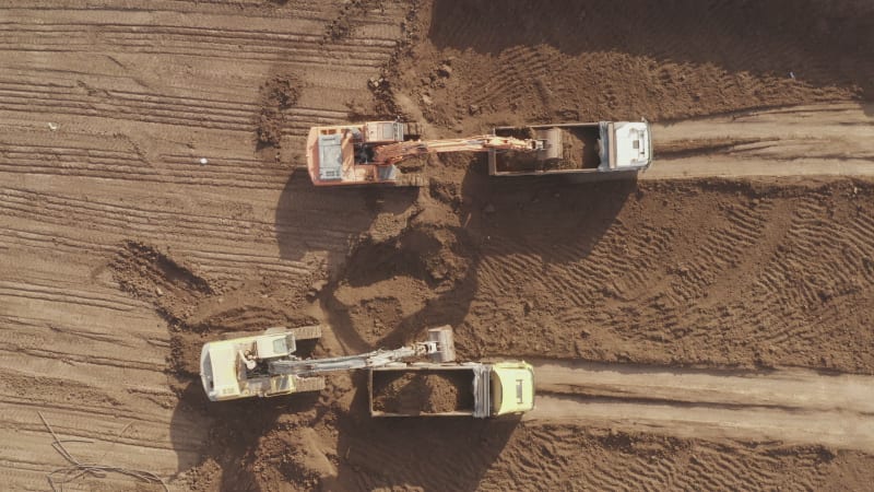 Excavators loading Trailer Truck with a load of Soil, Aerial view.