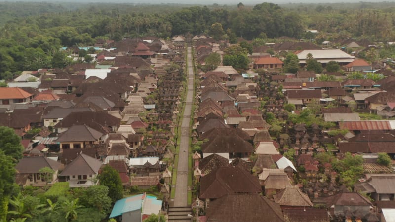 Flying above the main road through Penglipuran village, a traditional Bali village. Aerial dolly shot of residential houses in small rural village in Bali, Indonesia