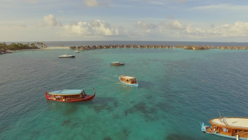 Aerial view of three traditional boats anchored next to Maldives island.