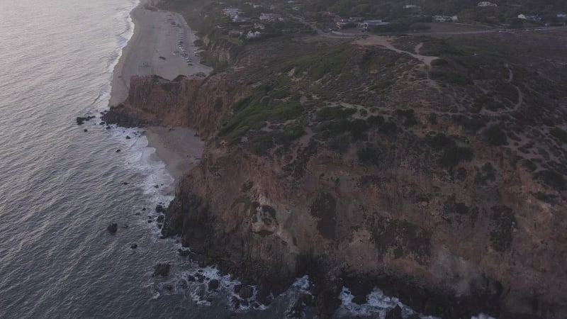 AERIAL: flight over Malibu, California view of beach Shore Line Pacific ocean at sunset with mountain cliff