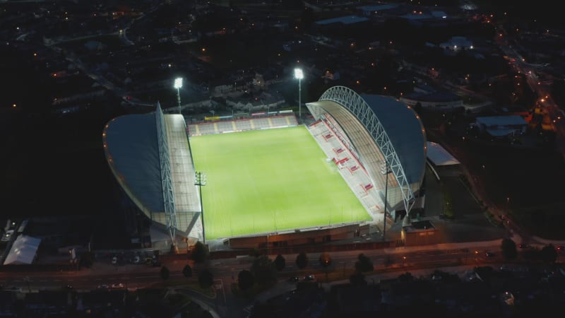 Aerial view of football stadium glowing into night. Bright lights illuminating green playground. Limerick, Ireland