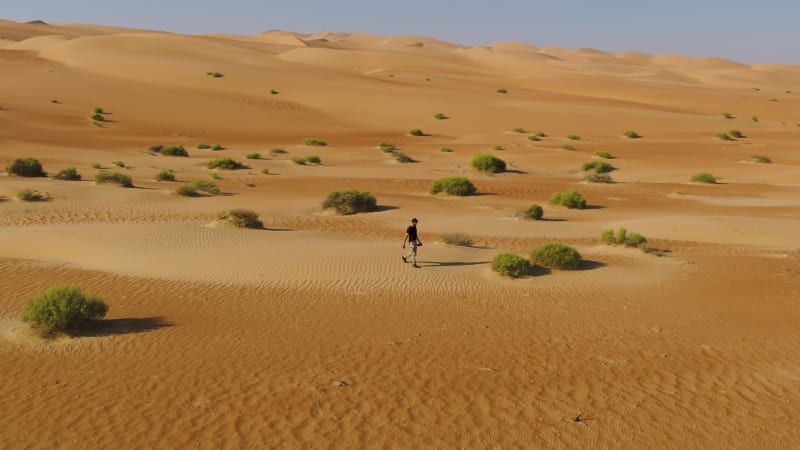 Aerial view of a man walking alone in the dunes of Sharjah desert.