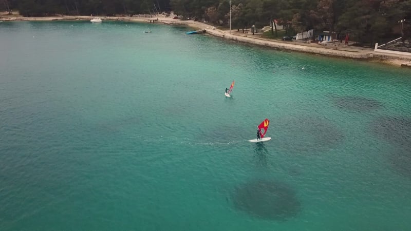 Aerial view of man practicing kitesurfing at transparent water.