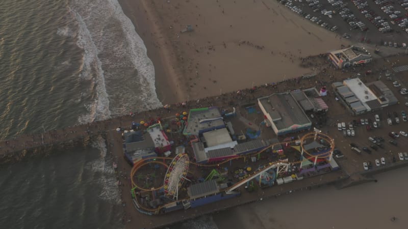 Famous Santa Monica Pier, California from an Drone Perspective at Sunset with Tourists, Pedestrians having fun at theme park and Ferris Wheel, Birds Eye View Overhead Top Down Shot