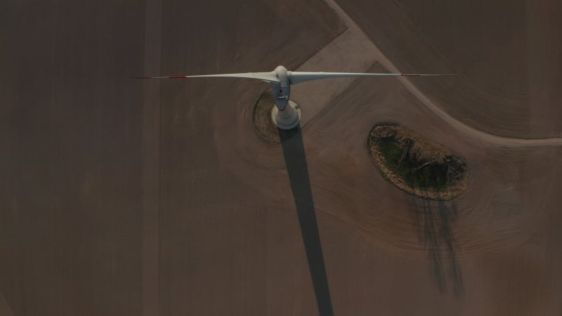 Close up Overhead shot of wind Turbine, Mill rotating by the force of the Wind Generating Renewable Energy in a Green Ecologic way for the Planet over beautiful Green Agriculture field