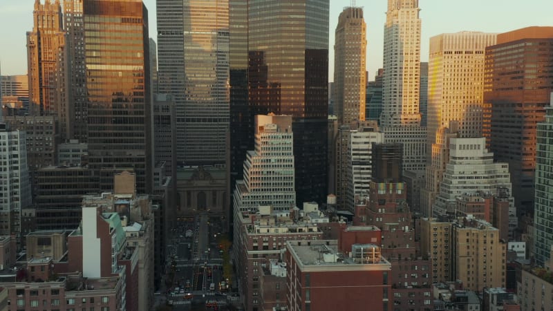 Forwards fly above buildings in midtown. Modern skyscrapers with glossy facades reflecting colourful sunset sky. Manhattan, New York City, USA